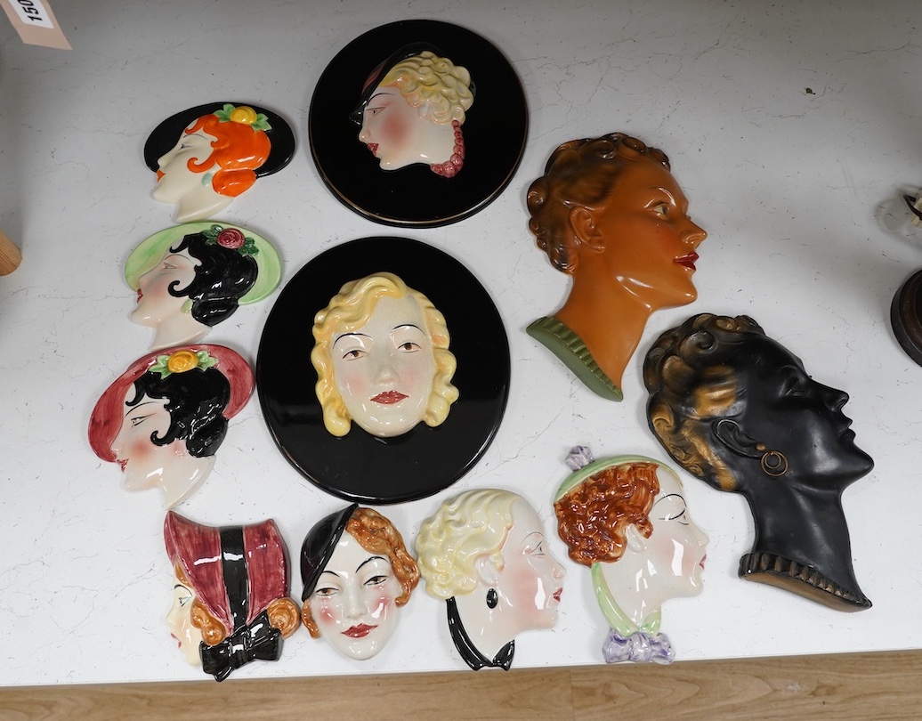 Six Art Deco style composition and pottery wall masks, largest 30cm high. Condition - fair, one mask detached from plaque